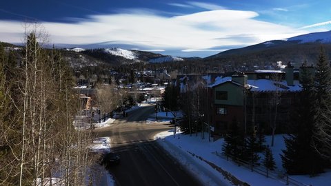 Aerial forwarding shot of a down main street in Colorado, United States during the winter season. View of big building and residential houses on either side of the road.