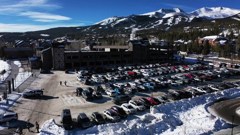 Cars In Parking Spaces At Ski Resort and Lodges In Snow During Winter In Steamboat Springs, Colorado. aerial drone descend.