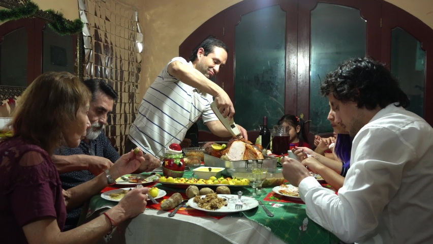 closeup cutting a cooked turkey with an electric knife and tongs at a family christmas dinner sitting down eating in 4k