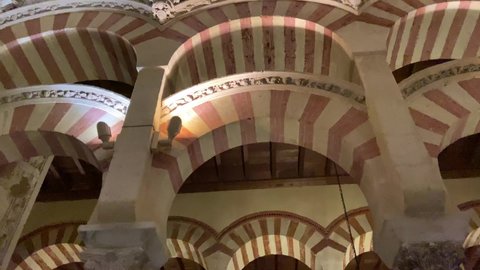 Cordoba, Spain, September 13, 2021: TILT SLOW MOTION - Interior view of the Mosque-Cathedral Monumental Site of Cordoba. The famous Red and white arches of La Mezquita.