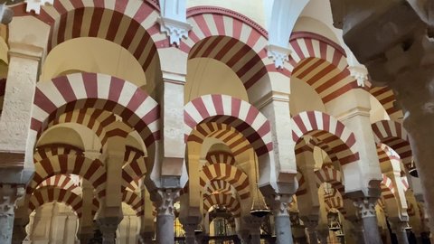 Cordoba, Spain, September 13, 2021: DOLLY SLOW MOTION - Interior view of the Mosque-Cathedral Monumental Site of Cordoba. The famous Red and white arches of La Mezquita.