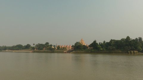The Dakshineswar Kali Temple is seen from the jetty ghat or ferry boat with the Hooghly River in the foreground.