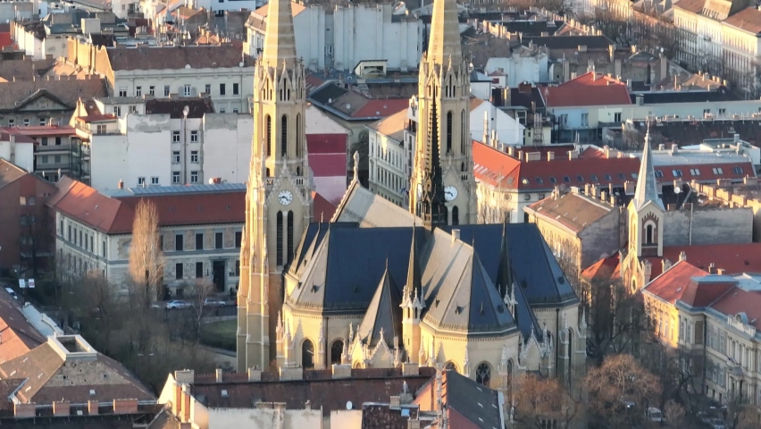 beautiful Saint Elizabeth church with two high church towers right in the center of Budapest in the middle of a residential area of ​​the Hungarian city during golden hour. Close up drone lifting shot
