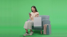 An Asian Shopping Woman Holding Shopping Bag Enjoy Using Mobile Phone Shopping Online While Sitting On Sofa In Front Of Green Screen
 - Powered by Shutterstock - Get 15% off with code: PIKWIZARD15