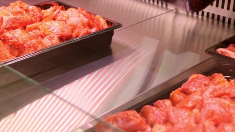 Lay out the pallet with the raw marinated meat on the window display in grocery store, close-up 4k footage