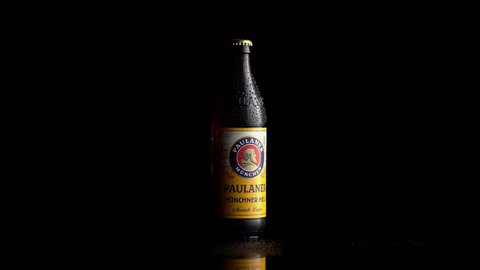 Munich, Germany - March 15, 2022: Paulaner Munich Lager labeled beer bottled rotating on a black background.