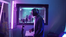 Close up shot of young African American rapper with dreadlocks singing in microphone in recording studio with purple light - Powered by Shutterstock - Get 15% off with code: PIKWIZARD15