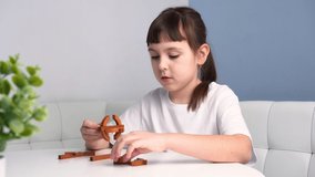 Cute child collects wooden geometric puzzle. Little girl plays with toy. Educational games concept