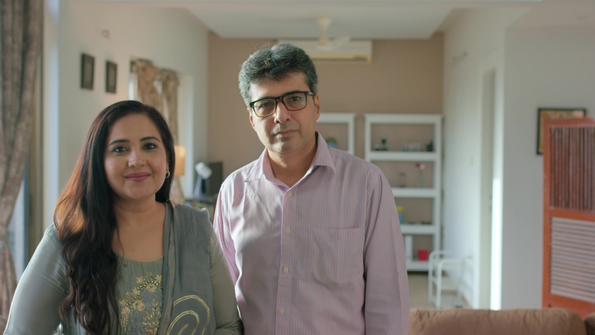 Smiling Indian Asian Modern Middle-aged Retired couple, family or Husband Wife standing together and looking at the camera and smiling in an interior house setup. Concept of Happy Married Life.  | Shutterstock HD Video #1088311049