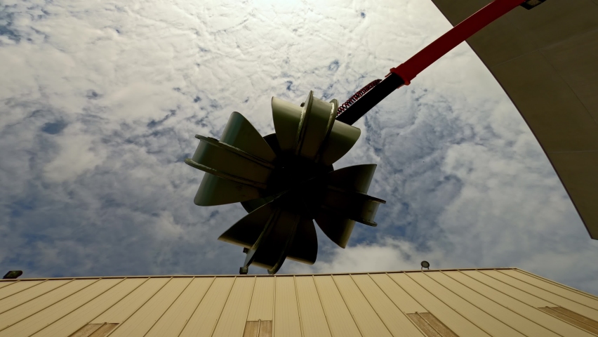 Claw on scrap metal seen from below with cloudy sky as it opens and closes its nails.
