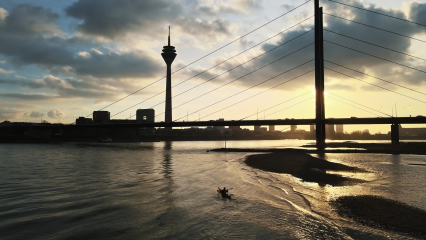 A man is canoeing at a sunset on the Rhine in Dusseldorf. Rhine tower of Dusseldorf Royalty-Free Stock Footage #1088314423