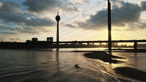 A man is canoeing at a sunset on the Rhine in Dusseldorf. Rhine tower of Dusseldorf