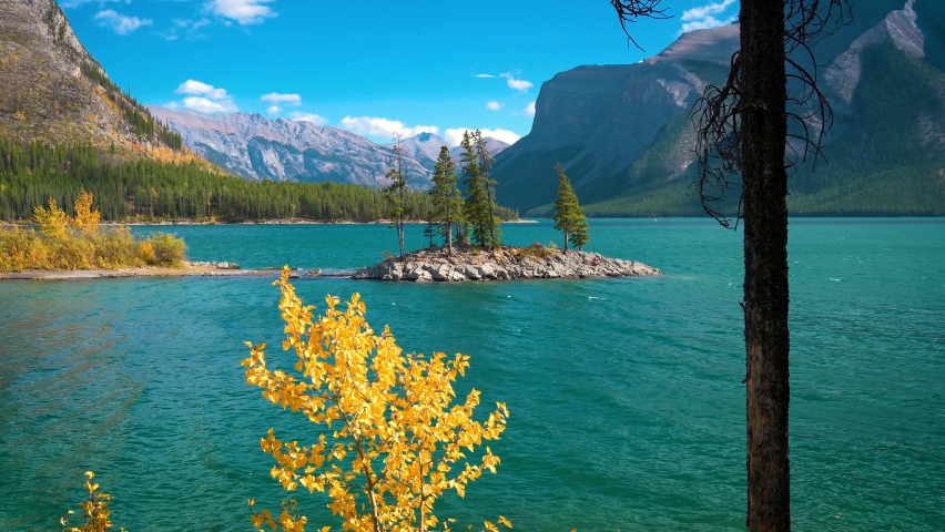Small island with trees on Lake Minnewanka in Banff National Park, Canada. Minnewanka is a glacial lake and the 2nd longest lake in the mountain parks of the Canadian Rockies. 4K UHD video.