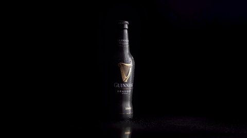 Dublin, Ireland - March 15, 2022: Irish Guinness dark beer in a bottle rotating on a black background and isolated.