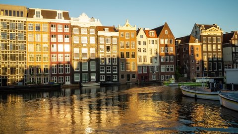 Amsterdam, Netherlands - 08-08-2019: Beautiful sunset lights on old building architecture in city center reflection in water, hyperlapse, time lapse