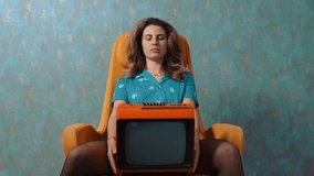 vintage style - young woman holding an old retro TV opens her eyes