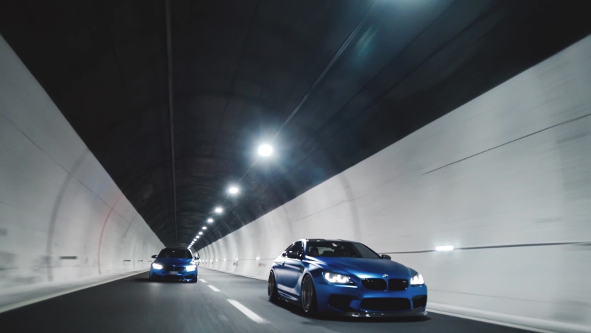 Chiusaforte Italy- 10.10.2021: Rolling shots of two cars BMW M3 and BMW M6 racing at high speed in a tunnel, Close up view of BMW custom cars  competition, driving fast in a tunnel