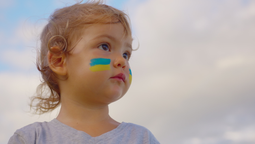 Close up portrait little baby with flag of Ukraine on face sitting alone. Protest against Russian war invasion in Ukraine. Ukrainian Flag, Protesters concept Royalty-Free Stock Footage #1088328011