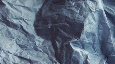 Thin creased blue background paper extreme close up rotating very slowly 