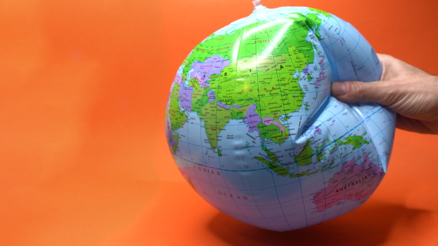 Hand tightly gripping an earth globe on orange background. Royalty-Free Stock Footage #1088331303