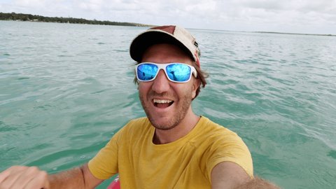 Man kayaking on turquoise clear waters takes cool selfie 