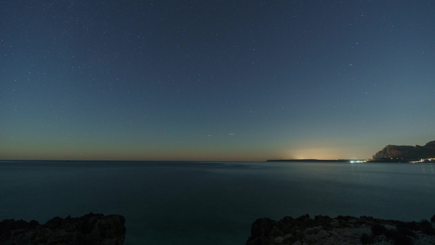 Stars at night over rocky coastline of mediterranean sea with clear turquoise water at nature reserve of monte Cofano, Sicily