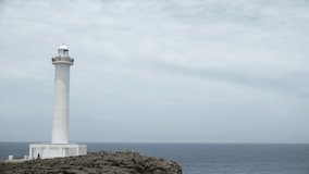 YOMITANSON, OKINAWA, JAPAN - AUGUST 2021 : View of lighthouse at Zanpa Misaki (Cape Zanpa) and East China Sea (Ocean) in daytime. Summer holiday, vacation and resort concept video.