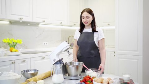A women cook adds a cottage cheese cream to prepare dough or cream in a mixer bowl. cooking courses. bread and dessert recipes. family business. online lessons for cooks.