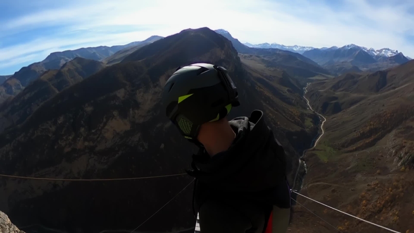 a man jumps from a mountain with a parachute, a jump from a cliff, a free fall