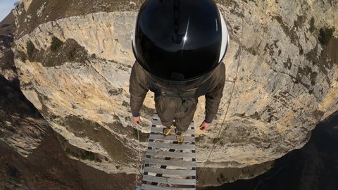a man jumps from a mountain with a parachute, a jump from a cliff, a free fall, helmet camera