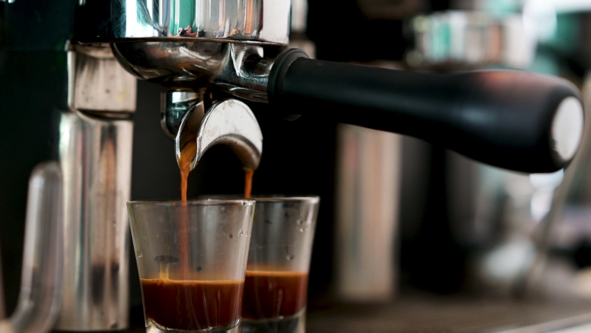 Pouring coffee stream from professional machine in cup. Barista man making espresso shot by bottomless, using filter holder. Flowing fresh ground coffee. Drinking roasted black coffee in the morning Royalty-Free Stock Footage #1088340877