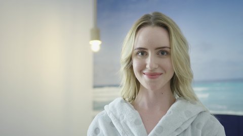 Young blonde caucasian woman re skin care face scrub mask revealing a clean hydrate and brighten skin looking straight in to the camera. health care spa luxury saloon treatment