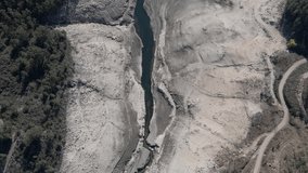 Aerial top-down forward over water basin during season dry, Aceredo dam in Spain