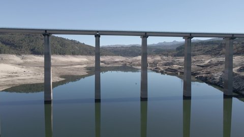 Drone flying between pylons of bridge on old dam of Aceredo during dry season, Spain. Aerial forward