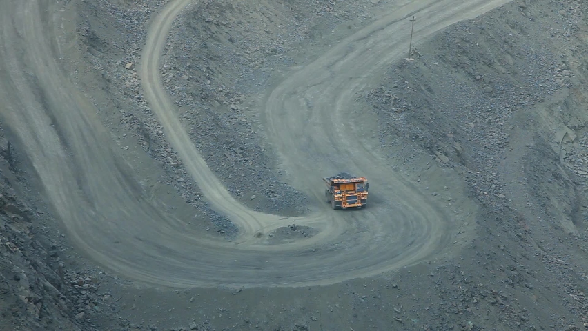 A mining dump truck drives on a road in a deep iron ore quarry. Iron ore mining. Visualization of a modern quarry. Royalty-Free Stock Footage #1088347235