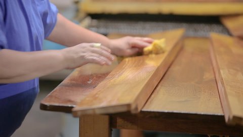 A woman varnishes wood products at a furniture factory. Furniture varnishing. Hand varnishing