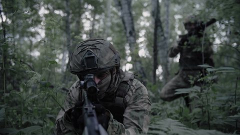 Detachment of armed soldiers with sniper rifles, in a dense forest on a special operation, protect the front line. Equipped soldiers in combat readiness.
