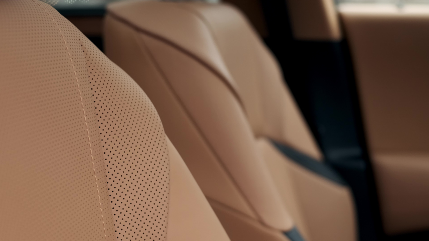 Close view of leather interior of luxury car, beige. Comfortable perforated seats in business sedan for comfortable ride. Royalty-Free Stock Footage #1088350259