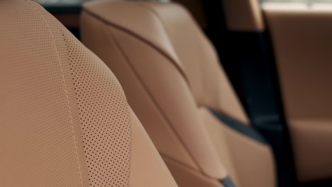 Close view of leather interior of luxury car, beige. Comfortable perforated seats in business sedan for comfortable ride.