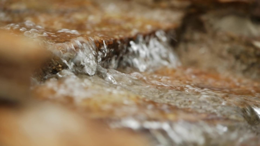 Close Up of Clean Water Flowing Over Rock - Shallow Depth of Field - Slow Motion