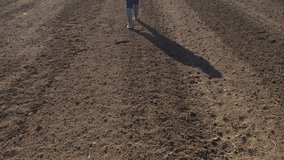 Rear view female farmer walking in ploughed field, drone footage with copy space included