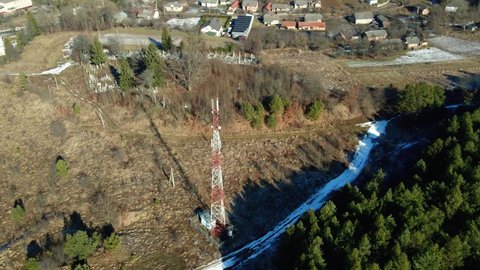 4G, 5G mobile tower overlooking the area near the green forest in the small town in winter, aerial view. Cell phone tower. Telecom tower antenna transmits the signals of cellular 5g 4g mobile signal.