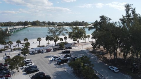 rising aerial looking south to Longboat Key in Sarasota, Florida. Busy parking at Coquina Beach park