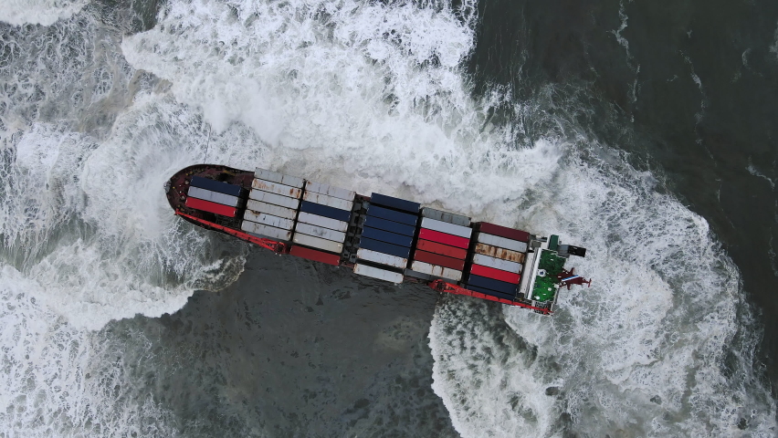 A drone view of the container ship, which ran aground during a storm. Shipwreck. Giant waves crash against the side of the ship, covering the ship Royalty-Free Stock Footage #1088358961