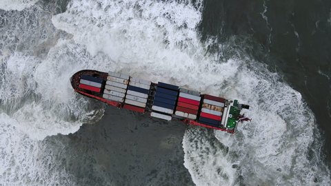A drone view of the container ship, which ran aground during a storm. Shipwreck. Giant waves crash against the side of the ship, covering the ship
