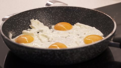 Cooking scrambled eggs on skillet. Woman stirring eggs on skillet to prepare scrambled eggs for breakfast. Cooking process. High quality 4k footage
