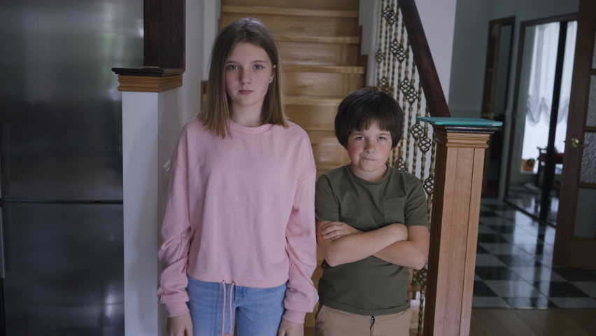 Portrait of sad teenage girl and little boy standing in living room as female hand gesturing scolding. Unrecognizable parent rebuking upset Caucasian sister and brother indoors Royalty-Free Stock Footage #1088363099