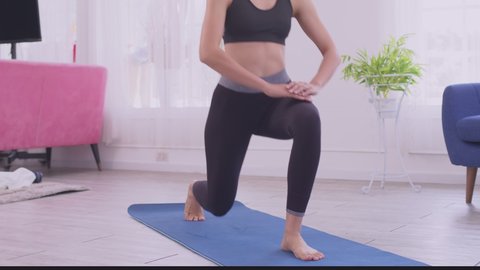 Asian woman do frontal lunges or squat exercise indoors in living room. Online indoors workout.