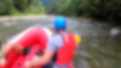 Rafting blurred background. Men sit in red inflatable boat, paddle and float mountain river, summer. POV. Extreme, entertainment, adventure in mountains. Rafting trip in rubber dinghy.