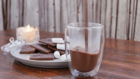 A woman's hand pours milk hot cocoa into a glass glass and adds marshmallow. Delicious drink with chocolate and vanilla aroma. slow motion - Powered by Shutterstock - Get 15% off with code: PIKWIZARD15